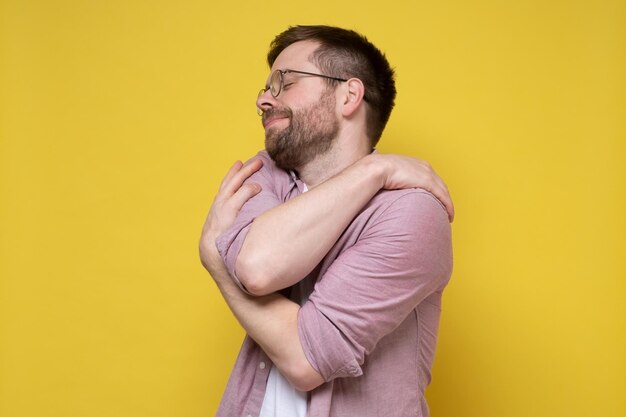 Funny bearded man in round glasses hugs himself he suffers from narcissism