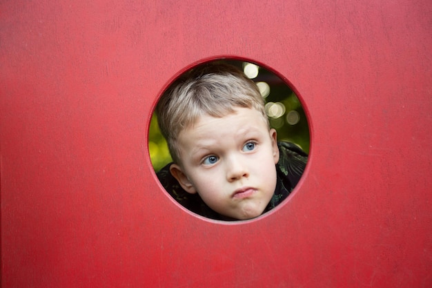 Funny boy looking through the hole on the playgroundCopy space for text or design