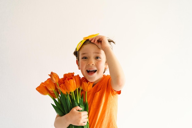 Funny boy with orange tulips and in the mask of a chick on white background