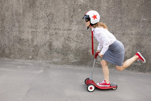 Funny businesswoman riding scooter outdoor