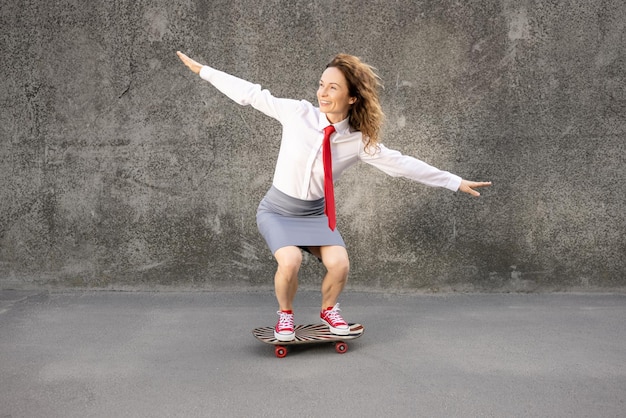 Funny businesswoman riding skateboard outdoor