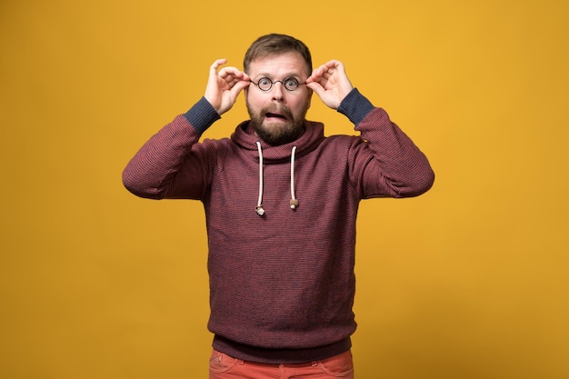 Funny Caucasian bearded man put on a toy rim of glasses without lenses and made a bizarre grimace