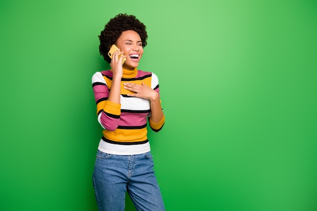  of funny cheerful dark skin wavy lady holding telephone near ear speaking best friend listen cool jokes stories wear casual striped jumper jeans 