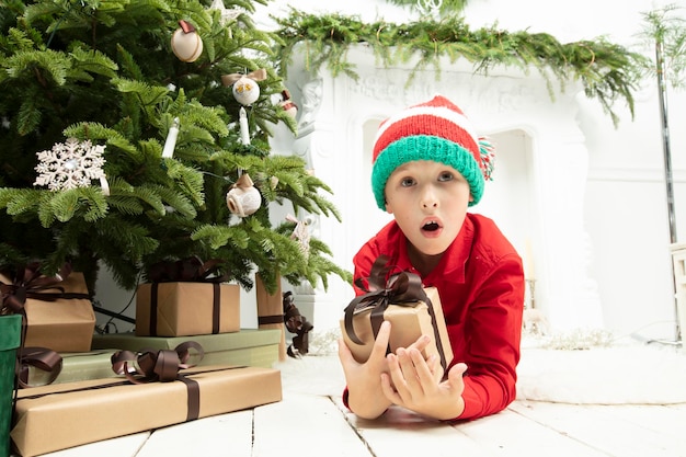 Funny child at christmas Boy in under the Christmas tree with gifts