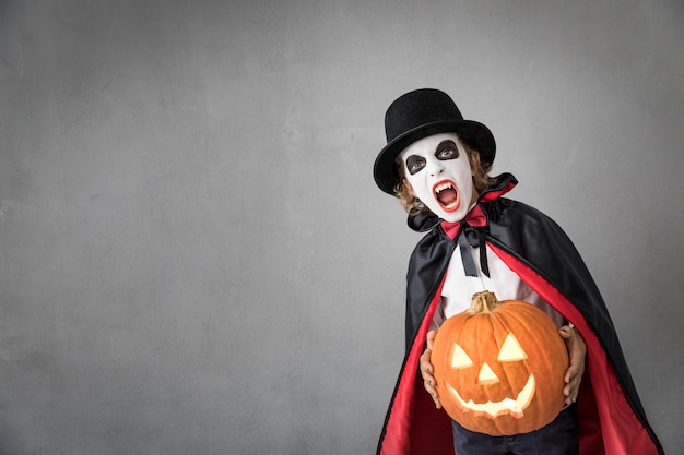 Funny child dressed Halloween costume. Kid painted terrible vampire. Autumn holiday concept