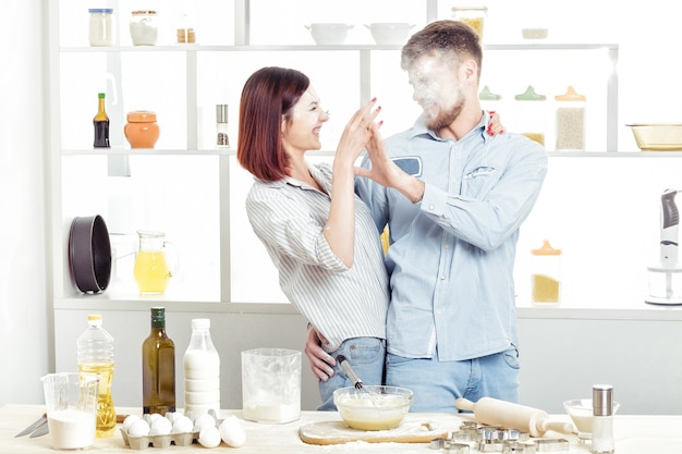 Funny Couple in love cooking dough and having fun with flour in the kitchen