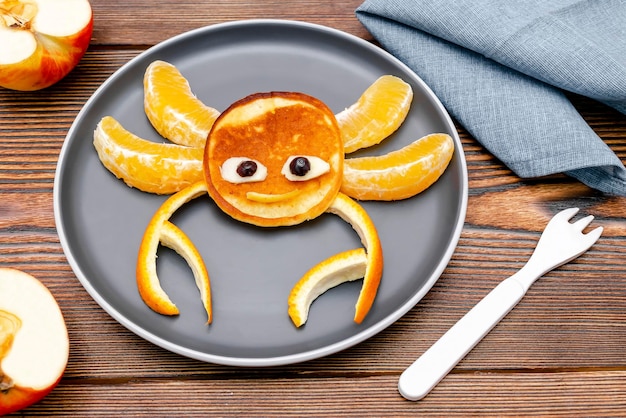 Photo funny crab face shape snack from pancake orangeapples on plate cute kids childrens baby's sweet dessert healthy breakfastlunch food art on wooden backgroundtop view