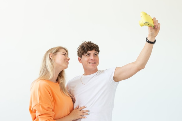 Funny crazy young couple blonde girl and a hipster guy taking a selfie on a vintage yellow film