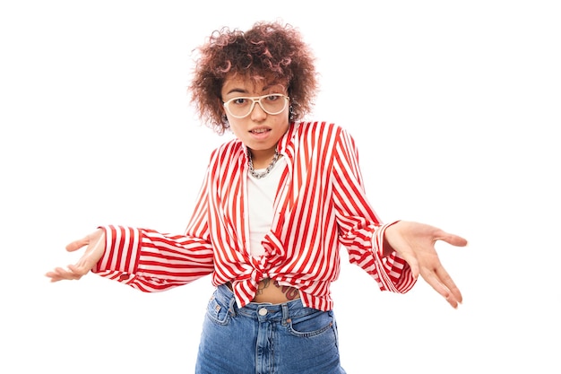 Funny curly girl shrugging hands thinks doubts makes decision isolated on white studio background