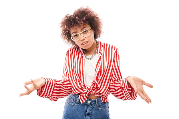 Funny curly girl shrugging hands thinks doubts makes decision isolated on white studio background