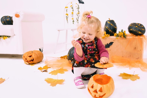 funny and cute little blonde curve girl with pumpkin in Halloween decoration