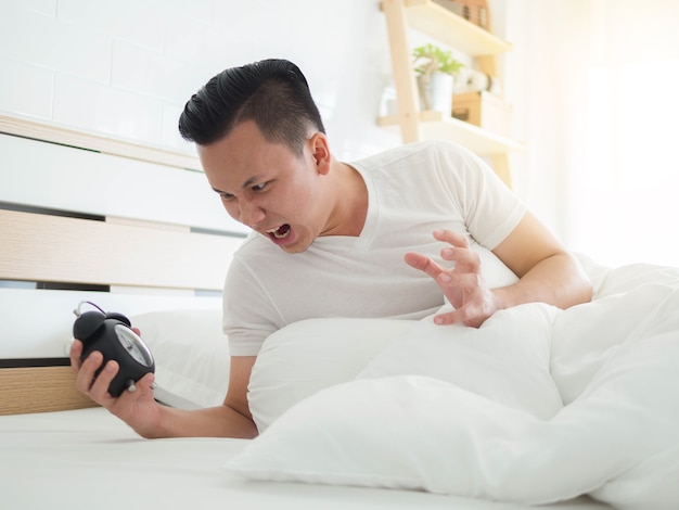 Funny face Asian man shocked as he wakes up late