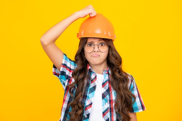 Photo funny face of little builder expert in helmet on construction site teen girl painter with painting brush tool or paint roller child on repairing work renovation concept