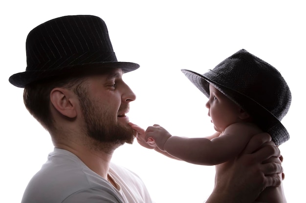 Funny father and kid in classic hats in backlight Father and little son