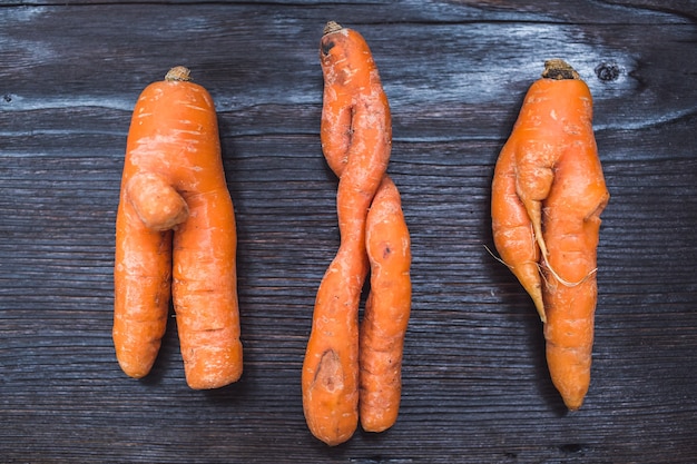 Funny forms of carrots on surface of dark board.