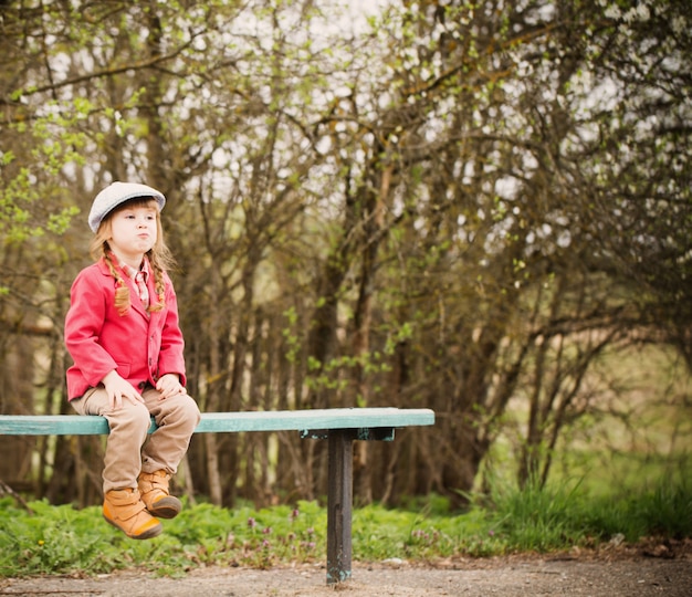 Funny girl on bench in spring park