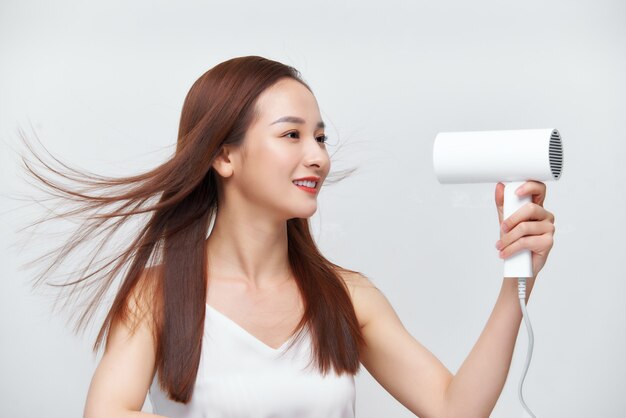 Funny girl drying her freshly washed hair looking in the mirror