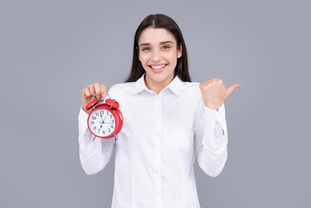 Funny girl hold alarm clock isolated on gray background