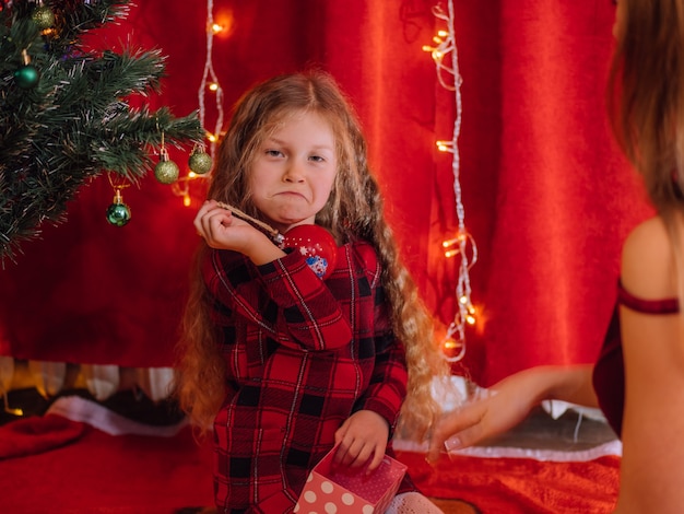 Funny girl near Christmas tree at home