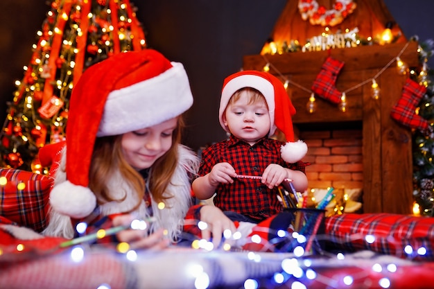 Funny girl in Santa hat writes letter to Santa and her liitle brother