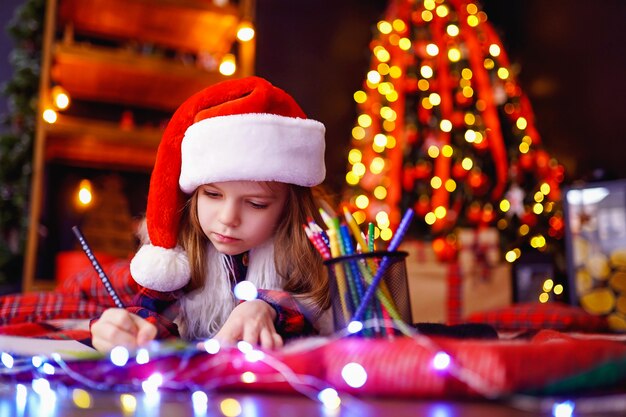 Funny girl in Santa hat writes letter to Santa