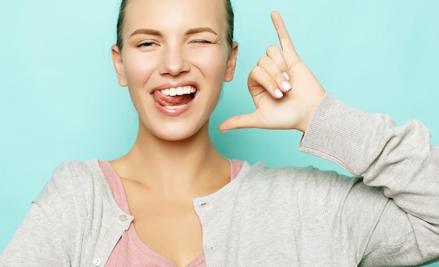 Funny girl showing her tongue while posing against studio background Emotional positive young female making faces