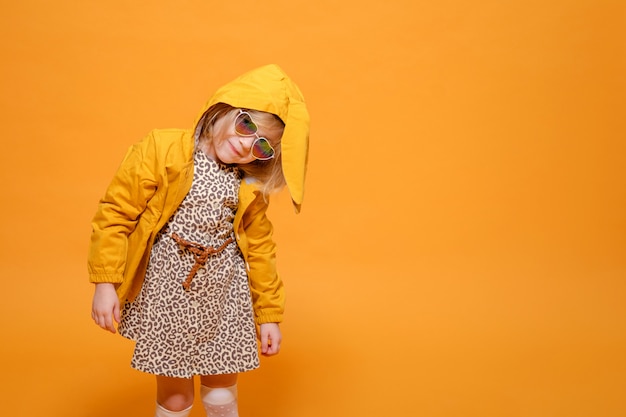 Funny girl in yellow raincoat with rabbit ears on yellow background