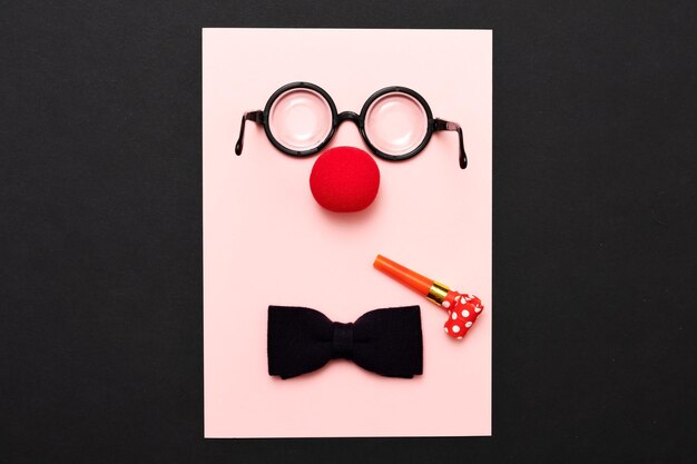 Funny glasses red clown nose and tie lie on a colored background like a face