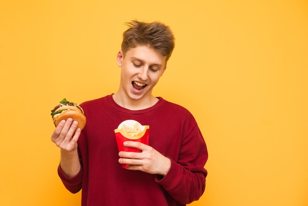 Funny guy holds fries and a burger on the yellow