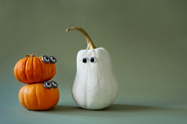 Funny Halloween pumpkins with googly eyes on green