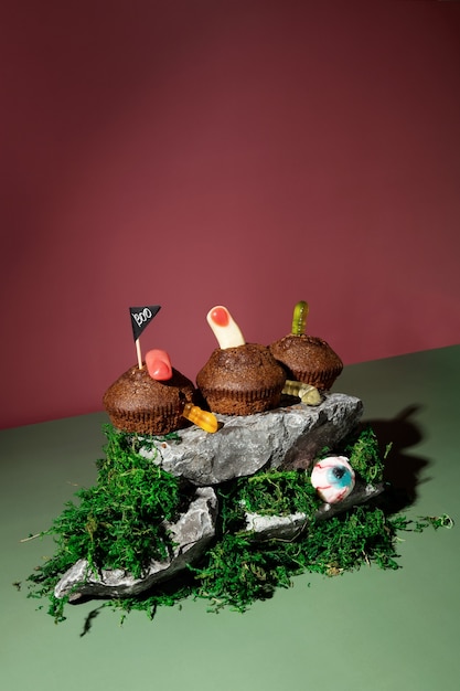 Funny Halloween scenery. Terrible threats. Cupcakes with jelly worms and fingers stands on stones and moss