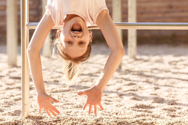 Funny Happy Child Girl Having Fun on Playground Outdoors. Upside Down Positive Kid . April Fools Day