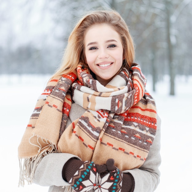 Funny happy young woman with beautiful smile in winter stylish clothes on  a snowy trees in the park. Cute girl fun spends time outdoors.