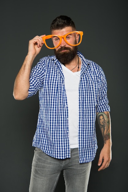 Funny hipster in extravagant glasses Fashion man with beard Playful guy enjoying party Funny glasses accessory Entertaining himself Only fun on my mind Bearded man wearing party glasses