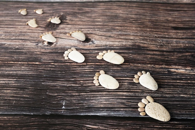 Funny human footprints from stones on a wooden background.