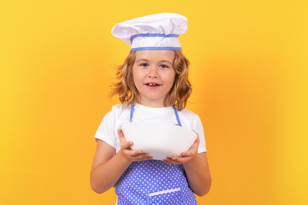 Funny kid chef cook with kitchen plate studio portrait Child chef cook studio portrait Kids cooking Teen boy with apron and chef hat