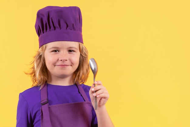 Funny kid chef cook with spoon studio portrait Portrait of little child in uniform of cook Chef boy isolated on studio background Cute child to be a chef Child dressed as a chef hat