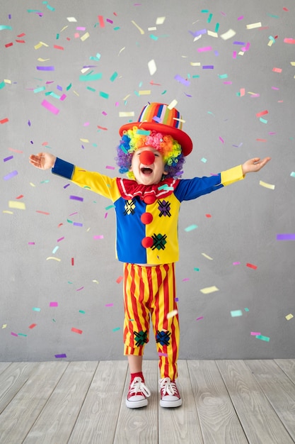 Funny kid clown against falling confetti.