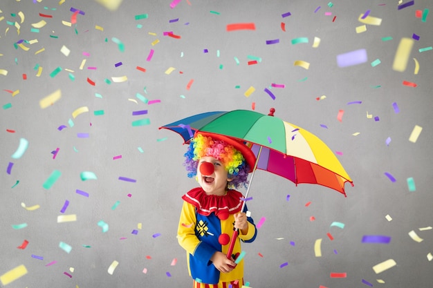 Funny kid clown against falling confetti.