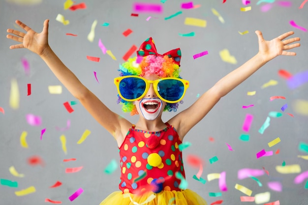 Funny kid clown with pper confetti. Happy child playing at home. 1 April Fool's day concept