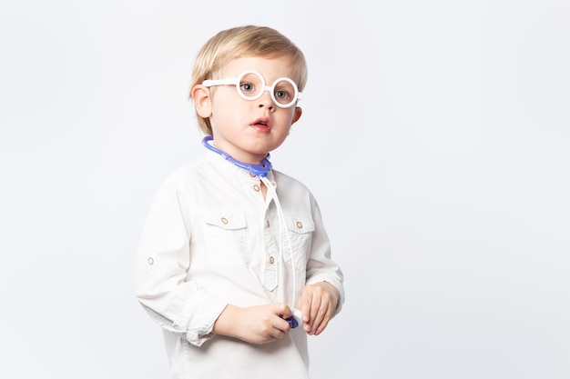 Funny kid doctor with glasses and stethoscope on light background with copy space.