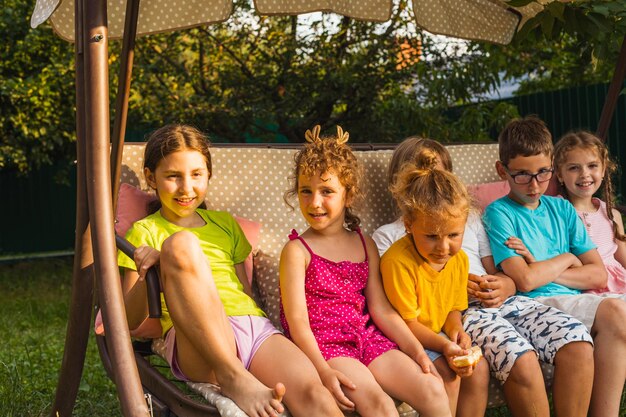 Funny kids resting on large garden swing