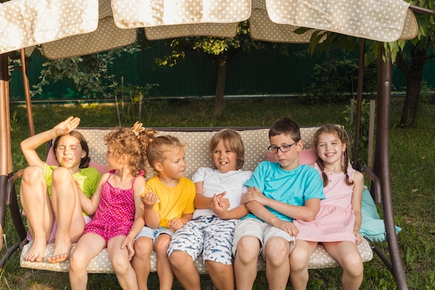 Funny kids resting on large garden swing