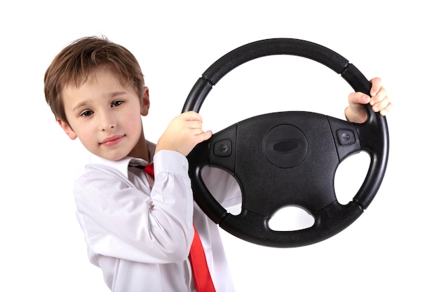 Funny little boy is holding a car steering wheel Young driver on a white background