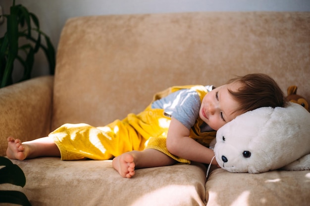 Funny little child is having fun playing with soft toys on the couch at home