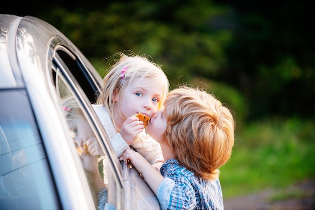 Funny little couple saying goodbye before car travel farewell child concept little boy gives kiss fo