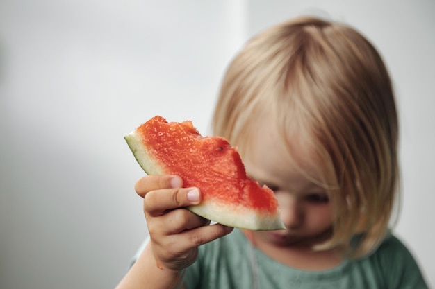 Funny little girl eating watermelon closeup