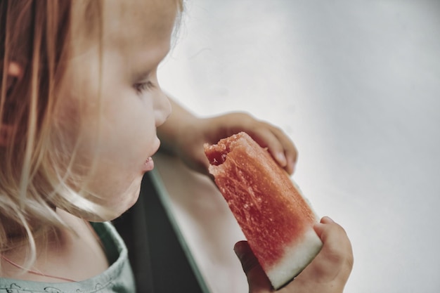 Funny little girl eating watermelon closeup