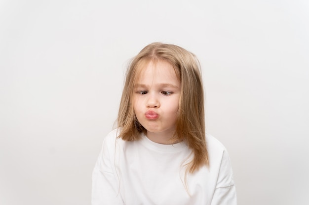 Funny little girl grimaces on a white background. happy childhood. vitamins and medicine for the child.