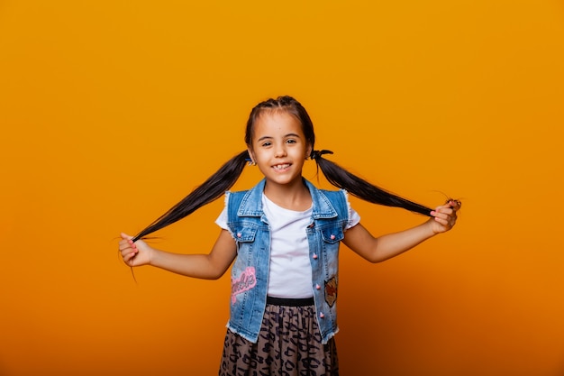 Funny little girl jumping and having fun on a colored yellow background.